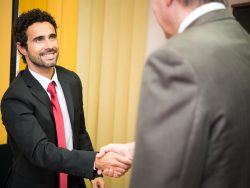 Un homme d'affaire souriant serrant la main à un autre homme d'affaire.