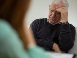 Vieux monsieur qui a l'air désespéré face à une jeune femme à une table