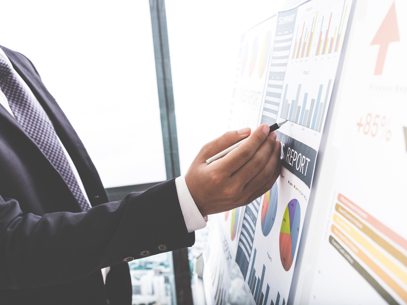 Un homme d'affaires qui réfléchit devant un tableau représentant des graphiques financiers.