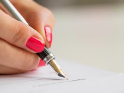 Une main de femme qui signe un document à la plume.