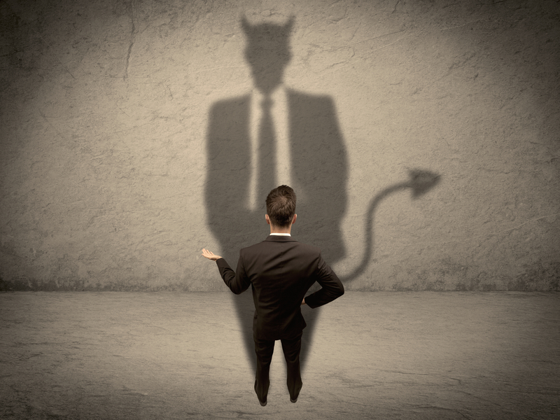 Un homme d'affaire face à un mur, son ombre ressemble à un diable.