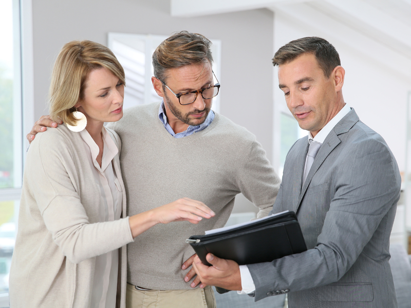 Un conseiller montrant un plan financier à un jeune couple.