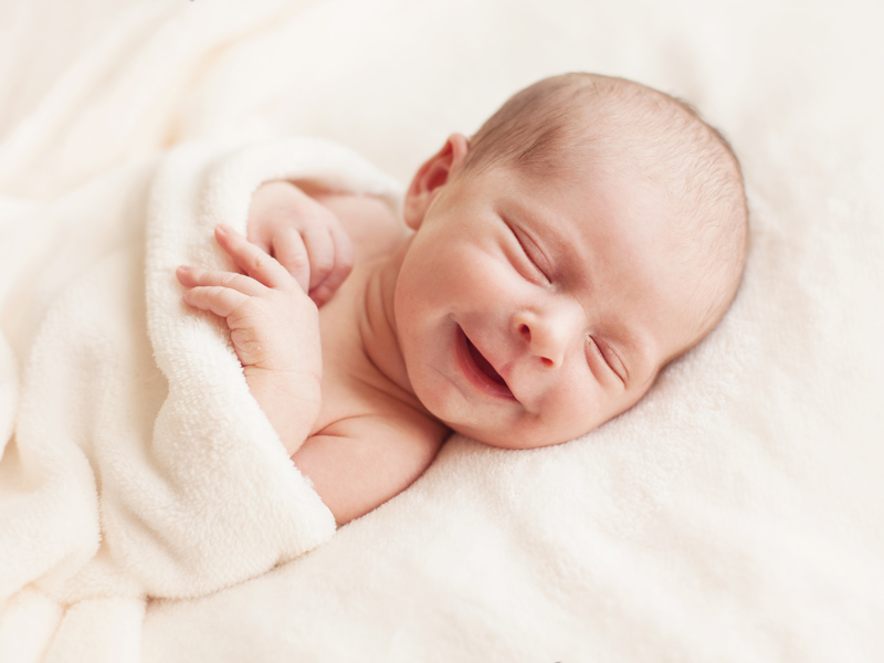 Un bébé souriant dans une couverture.