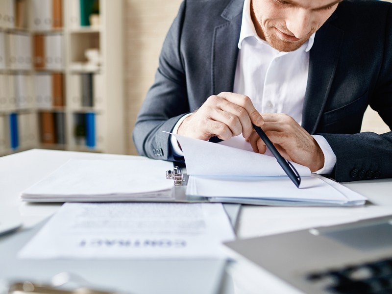 Un homme d'affaire assis à une table lisant des documents.