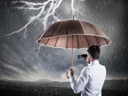 Un homme d'affaire avec des jumelles qui tient un parapluie sous un temps orageux.
