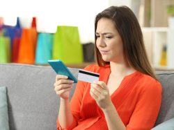 Une femme tenait une carte de crédit dans une main et son téléphone dans l'autre. Elle semble méfiante.