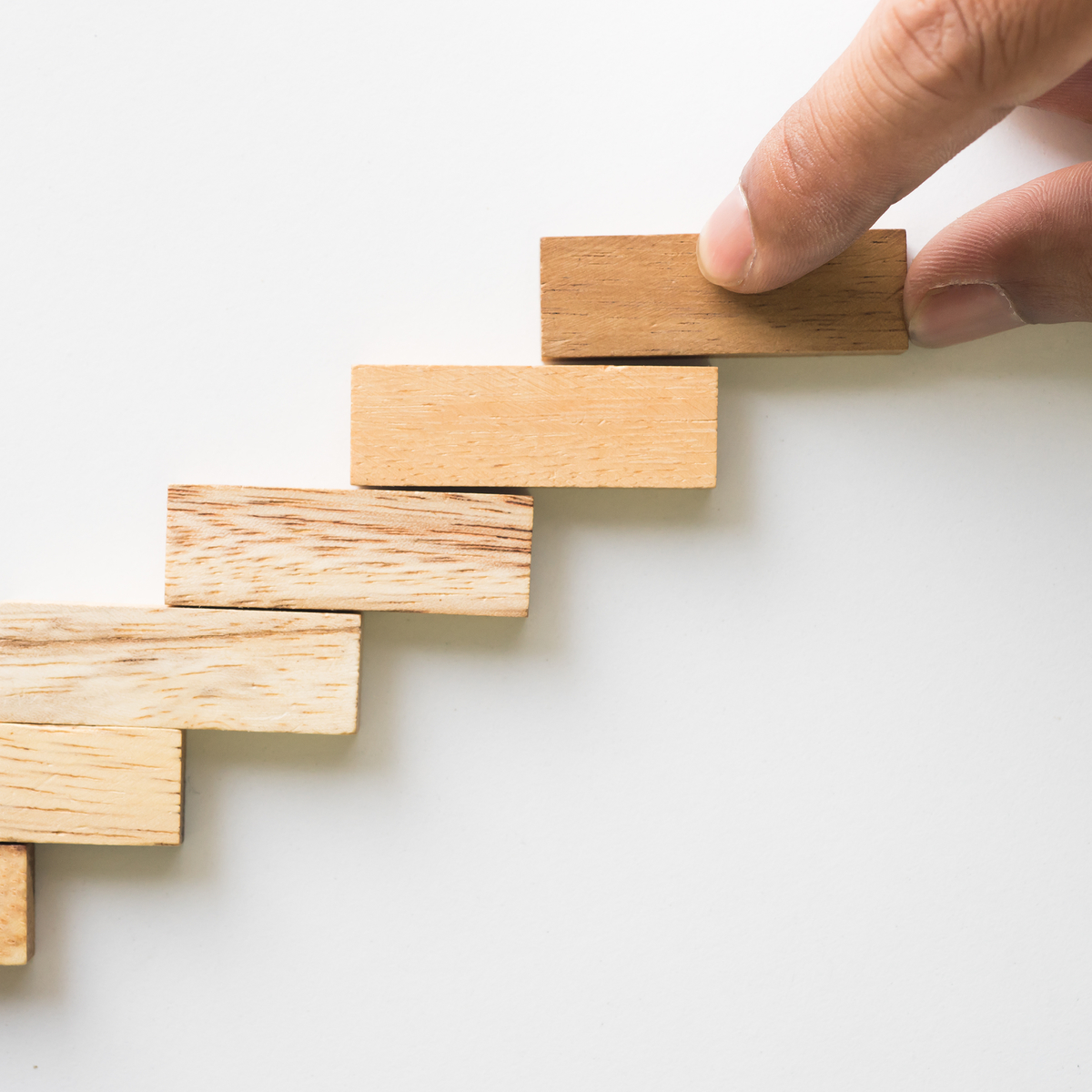 escalier fait en pièces de bois, une main ajoute une marche