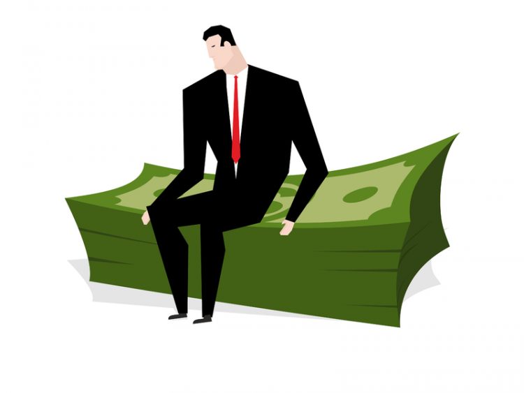 Un homme d'affaires assis sur un tas de billets vert.