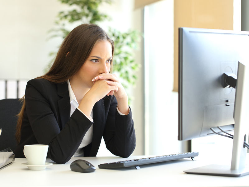 femme d'affaire réfléchit en regardant son écran d'ordinateur