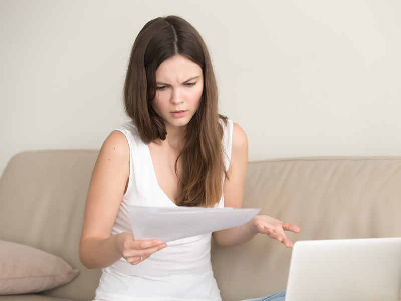 jeune femme qui regarde un papier avec l'air insatisfaite.