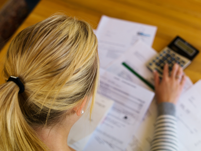 Une femme tapotant sur une calculette., des papiers devant elle.