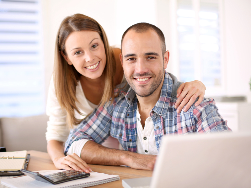 un couple souriant devant un ordinateur