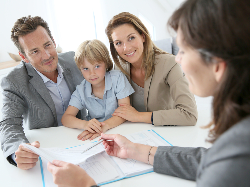 Une famille avec un père, une mère et un enfant qui regarde une conseillère qui leur explique des papiers.