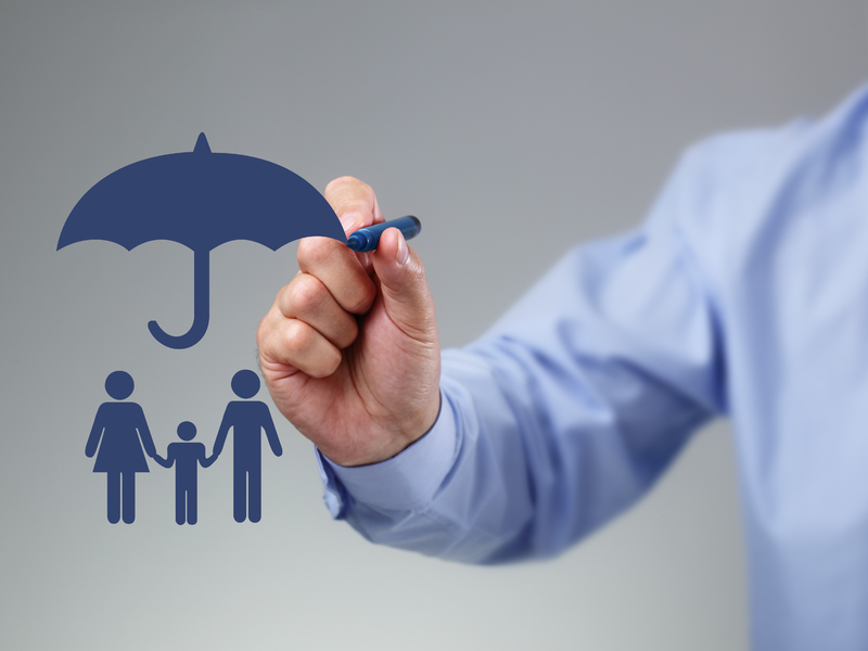 Un homme d'affaire avec un stylo qui retouche le dessin d'un parapluie protégeant une famille.