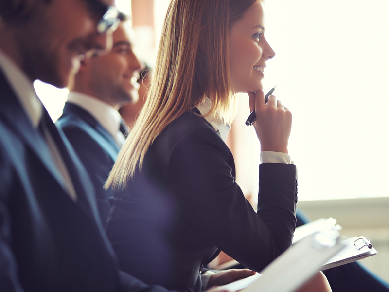 Une femme d'affaire intéressée qui prend des notes entre deux hommes d'affaire.