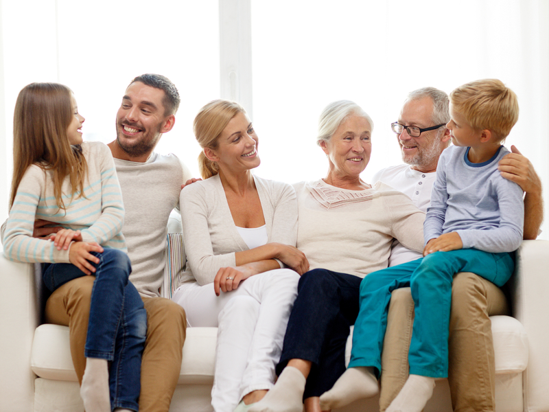 Une famille multigénérationnelle assise sur un canapé blanc.