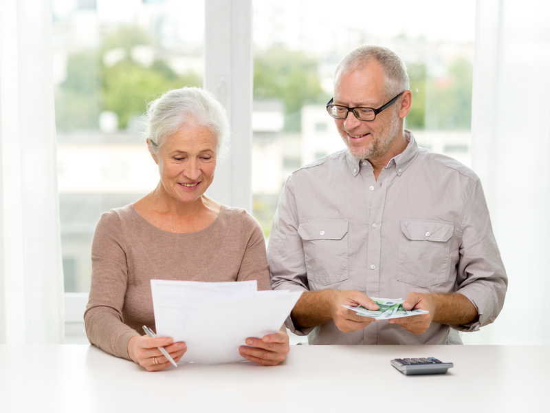 Un couple d'aînés qui regardent leurs papiers financiers avec l'air heureux.