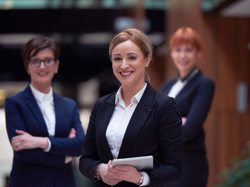 Trois femmes d'affaires faisant face à la caméra.