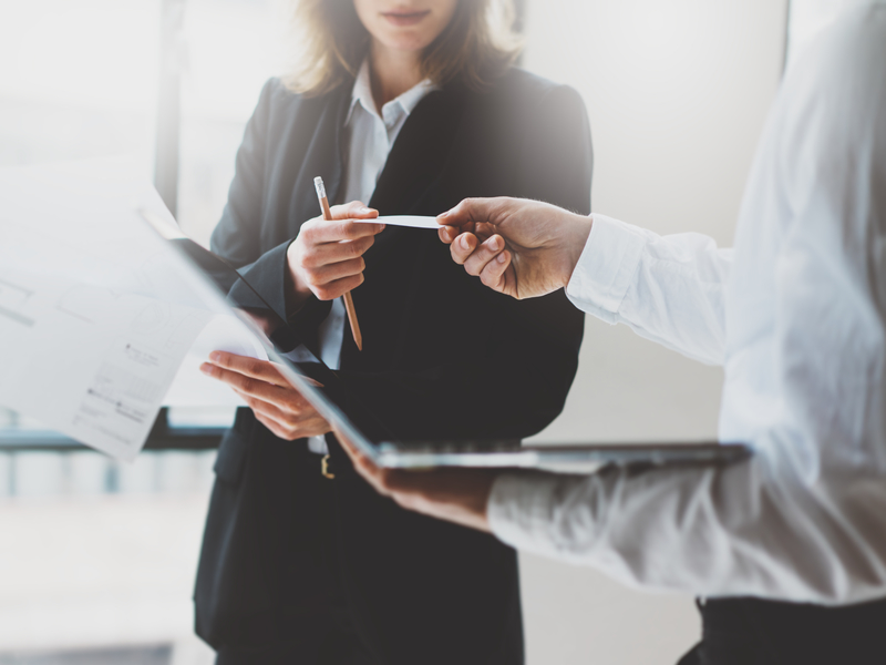 Un homme d'affaire donne une carte à une femme d'affaire dans un bureau.