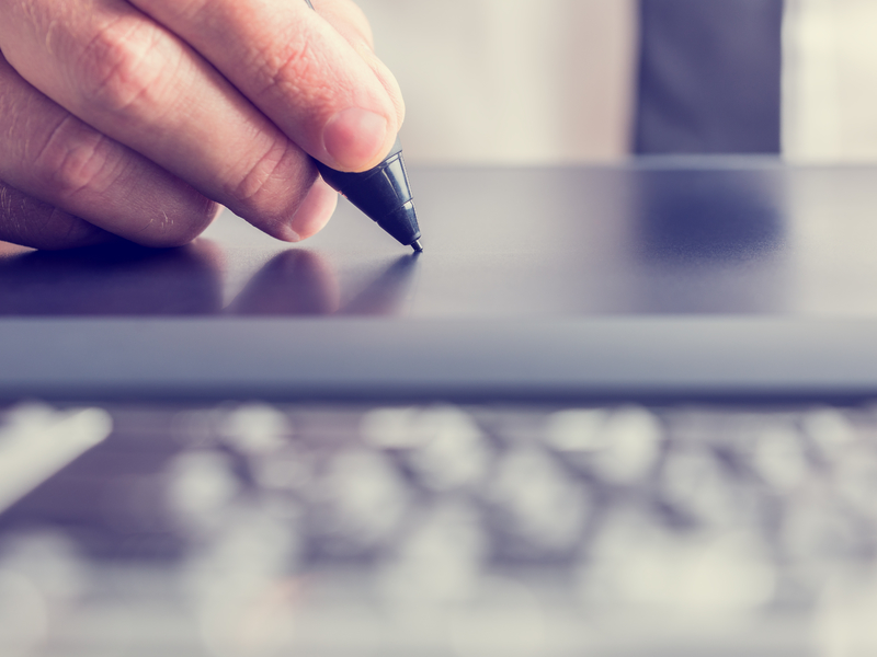 Un homme d'affaire signant sur une tablette électronique.