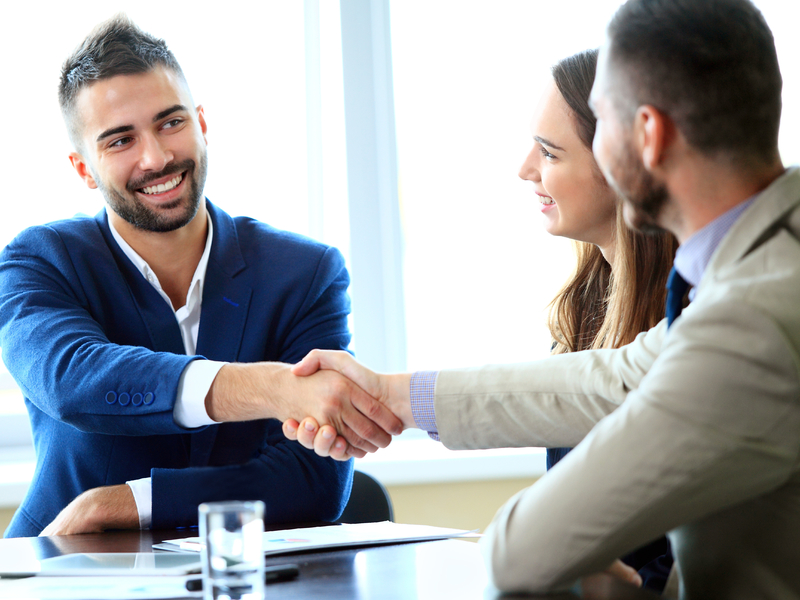 Un conseiller souriant avec un couple de clients.