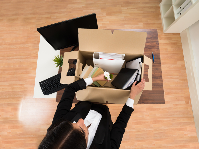 Femme d'affaire avec une boite dans les mains. Elle quitte son bureau.