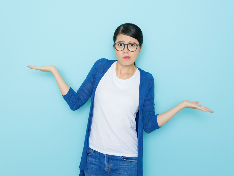 Une femme avec des lunettes qui hausse les épaules, ne sachant pas quoi choisir.