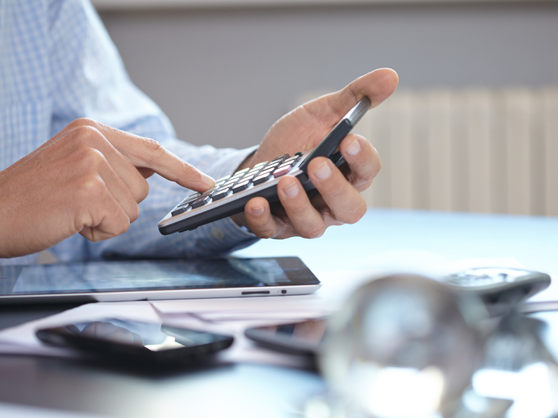 Un homme d'affaires à son bureau tapant sur une calculatrice.