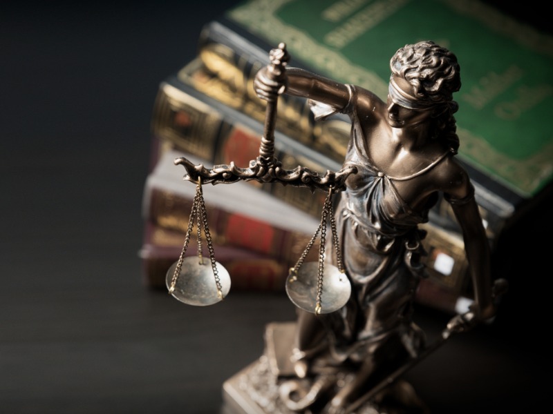 Une statuette en bronze de la déesse de la justice devant une pile de livre.