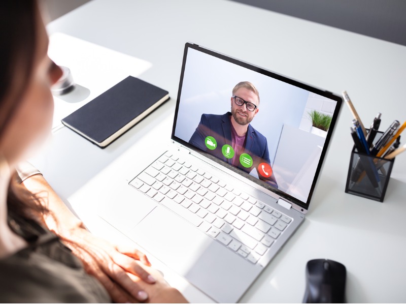 Une femme devant un ordinateur qui fait une vidéoconférence avec un homme d'affaires.