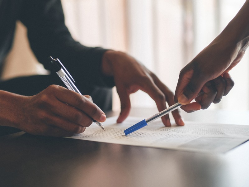 Une femme fait signer un document à son client.