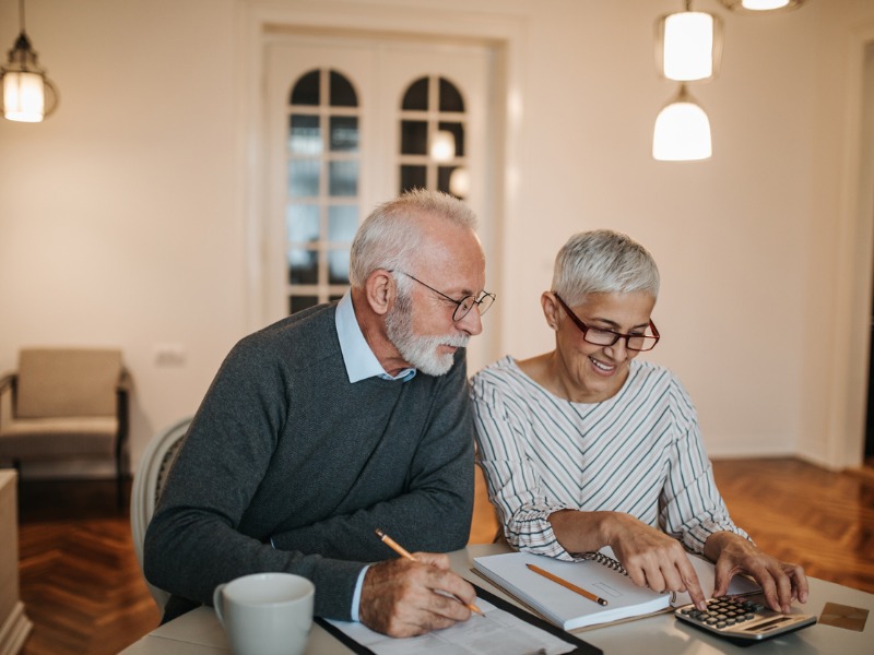 Un couple de personnes âgées avec une calculatrice et des feuilles.