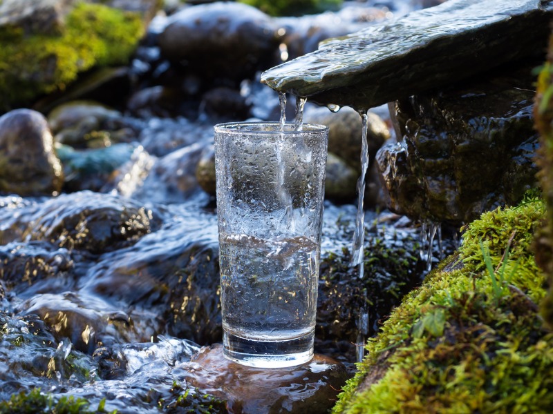 Un verre d'eau qui récolte l'eau d'une cascade.