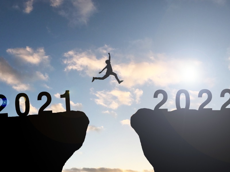 Un homme sautant d'une falaise où il est inscrit 2021 à une autre où il est inscrit 2022.