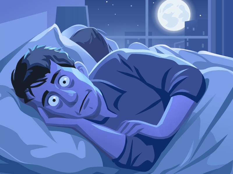 Un homme couché dans un lit les yeux grand ouvert.