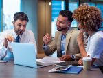 Trois personnes en tenue de travail se rencontrent et regardent un ordinateur portable sur leur lieu de travail.