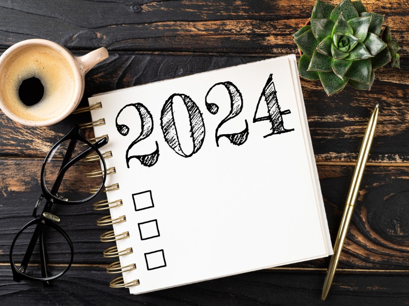 Liste des résolutions 2024 avec cahier, tasse de café sur table. Objectifs, résolutions, plan, action, concept de liste de contrôle.