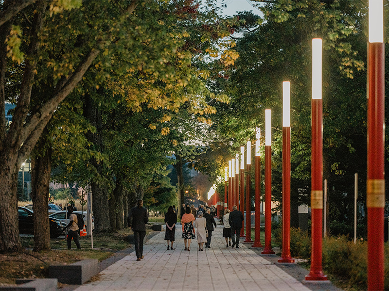 Individus d'allure académique marchant sur un sentier avec des lumières allumées.