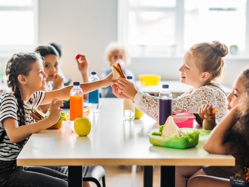 Écolières adorables prenant le déjeuner à la cafétéria de l’école.