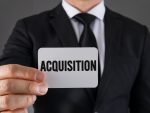 Un homme d'affaire tenant un carton dans les mains. Il y est inscrit acquisition.