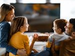 Famille heureuse mangeant le pop-corn tout en regardant la TV à la maison.