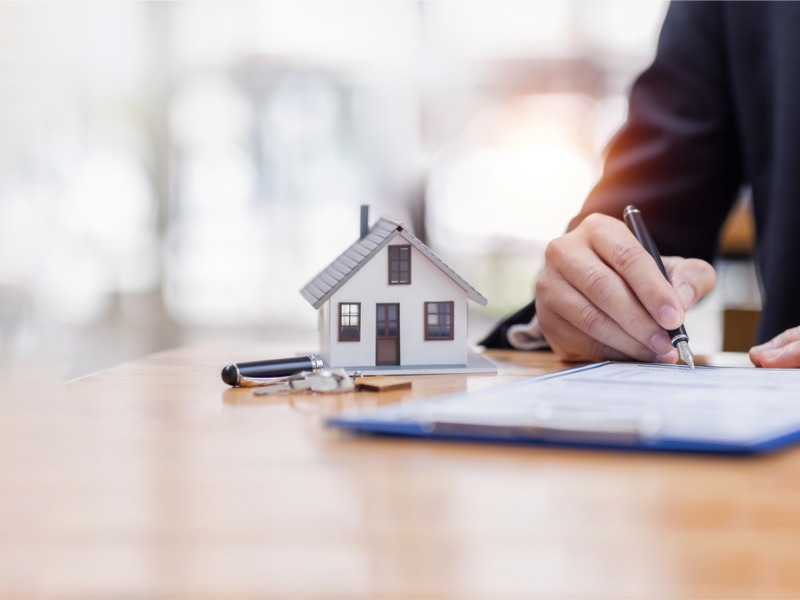 Modèle de maison avec homme d’affaires signe un contrat d’achat ou une hypothèque pour une assurance habitation d’achat et de vente concernant le prêt hypothécaire Concept immobilier, espace de copie pour le texte de l’éditeur.