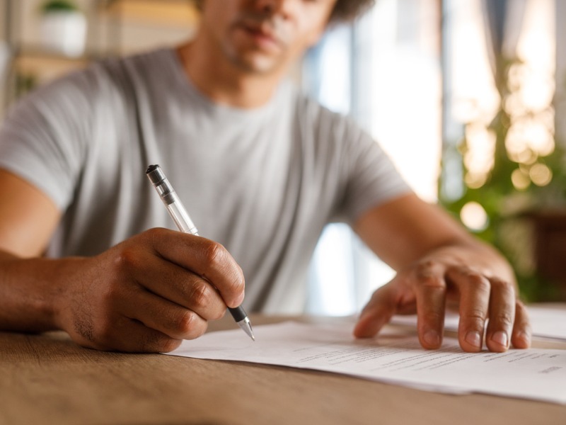 Homme assis à table, examinant des documents et signant des contrats