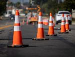 Cônes de signalisation sur la route avec flèche électronique pointant vers la droite pour dévier la circulation et voiture blanche en distance.