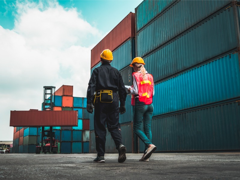 Un travailleur industriel travaille avec un collègue au chantier de conteneurs maritimes à l’étranger. Gestion de la chaîne d’approvisionnement logistique et concept d’exportation internationale de marchandises.