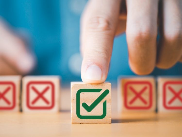 Appuyez à la main sur le symbole vert correct du signe devant le signe de la Croix-Rouge sur un cube de blocs de bois pour la proposition commerciale et le concept d’approbation de document.