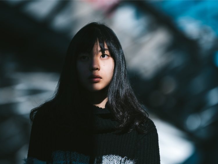 Portrait de jeune femme asiatique, la moitié de son visage est dans l'ombre.