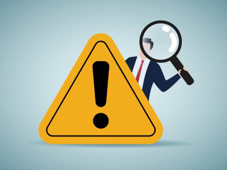 Un homme munit d'une loupe qui surgit de derrière un panneau attention.
