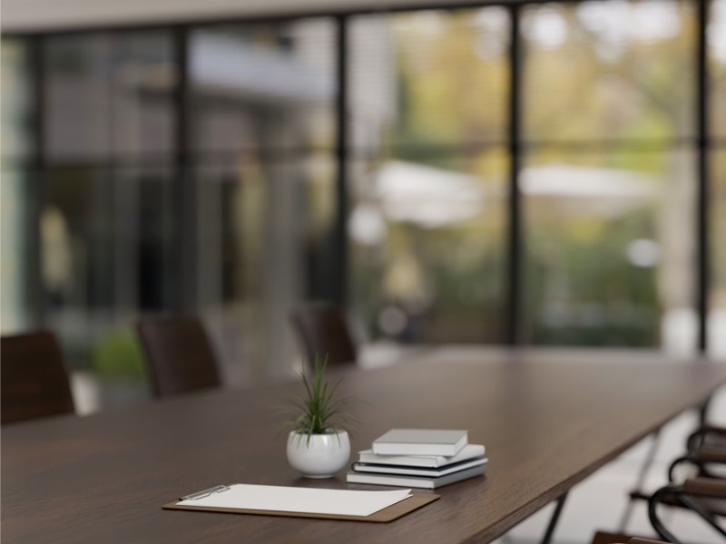 Image en gros plan d’une table de réunion en bois dur dans une salle de réunion moderne et spacieuse. Espace de travail professionnel.