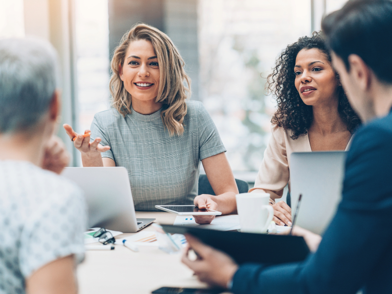 Conseillers assis autour d'une table avec des ordinateurs portables, discutant ensemble.
